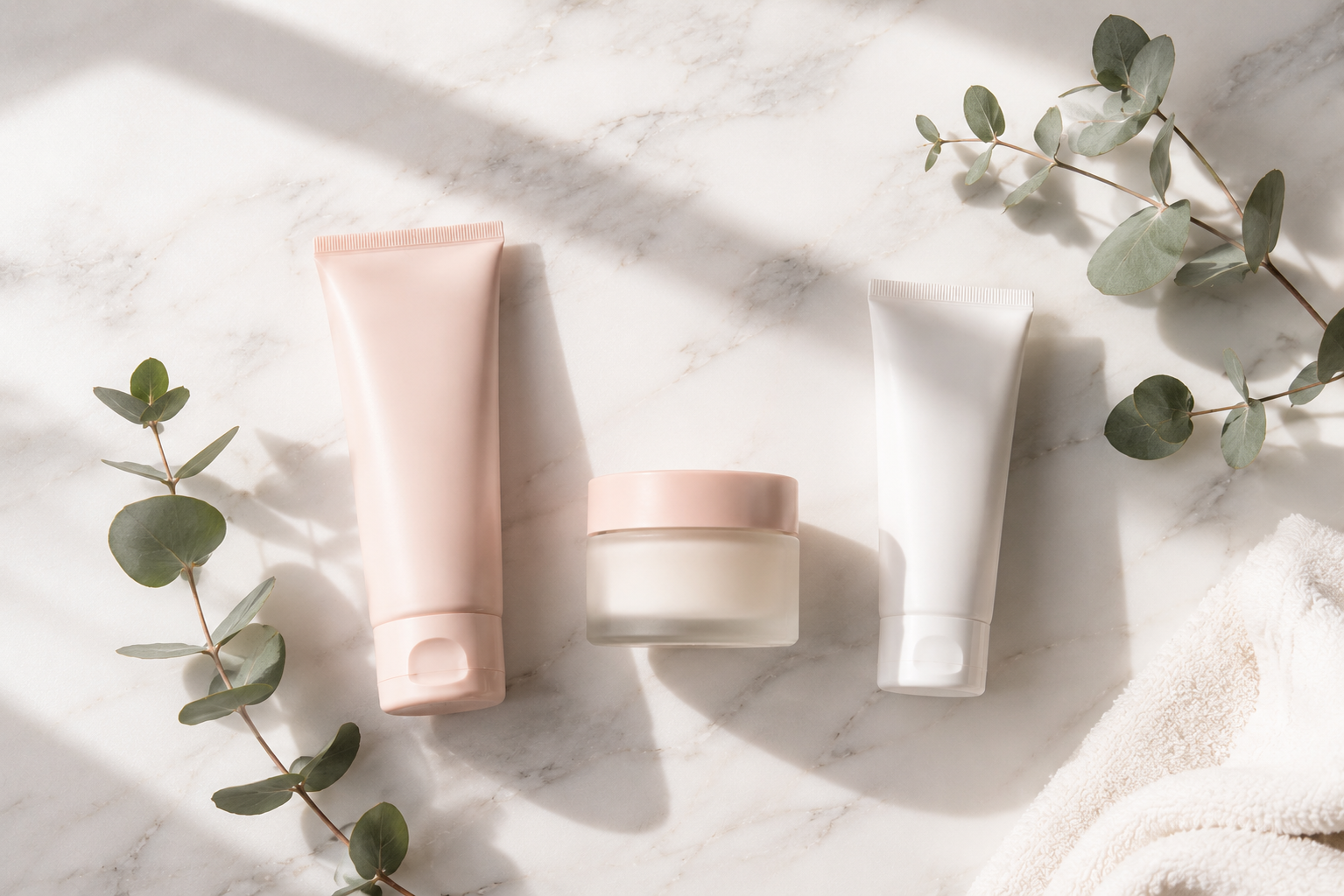 produtos essenciais de skincare minimalista sobre mármore com galhos de eucalipto